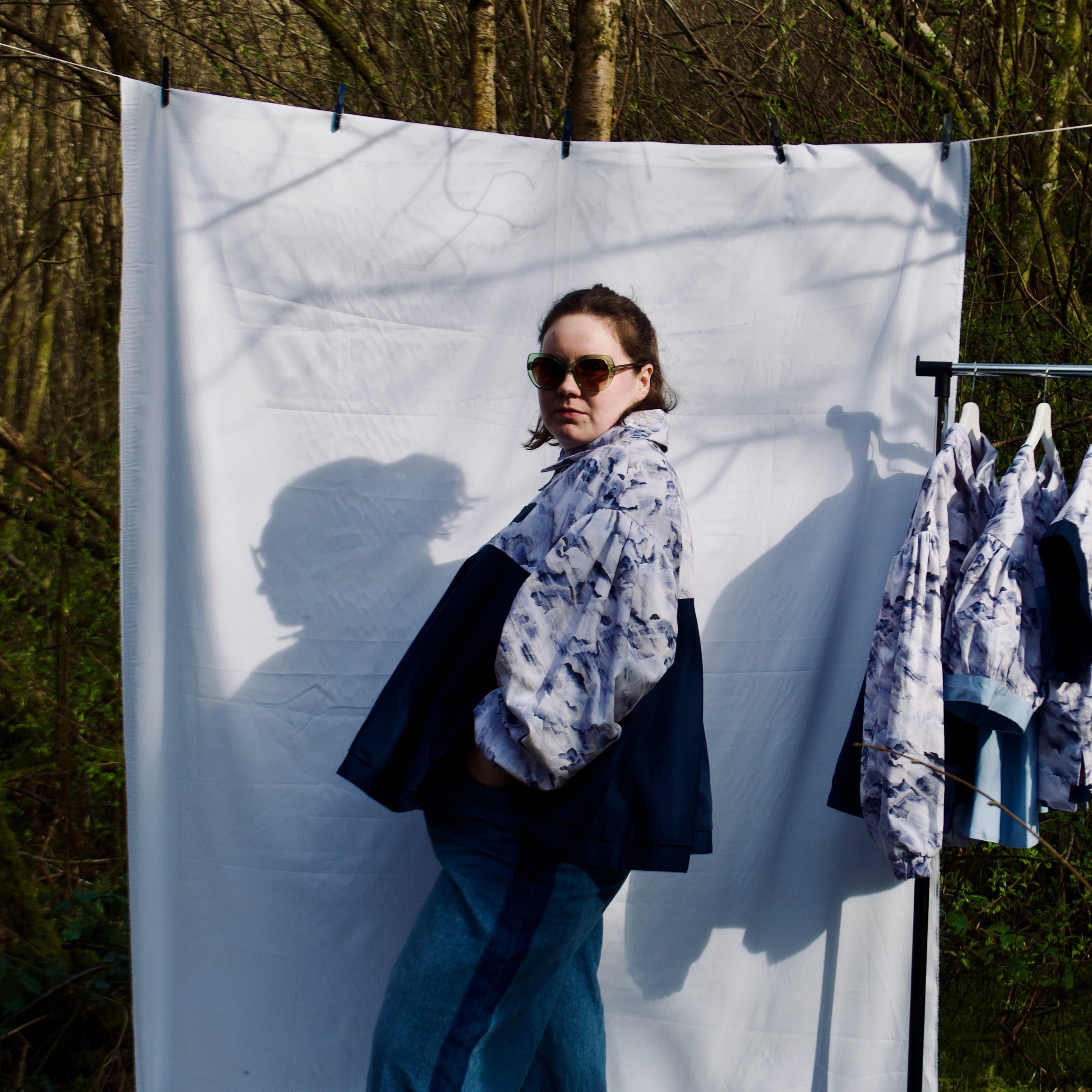 lightweight sustainable bomber jacket for women with blue and cream cloud print and navy contrast. long sleeves, elastic cuffs, collar, zip closure and breast pocket, oversized fit. casual spring summer jacket for women