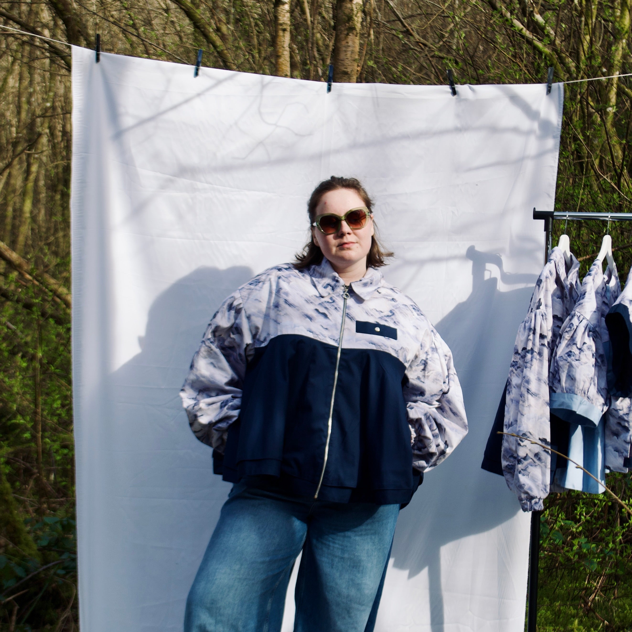 lightweight sustainable bomber jacket for women with blue and cream cloud print and navy contrast. long sleeves, elastic cuffs, collar, zip closure and breast pocket, oversized fit. casual spring summer jacket for women