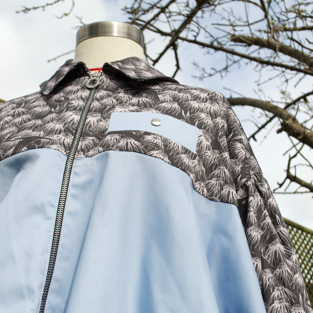 handmade sustainable lightweight jacket for women 100% cotton patterned fabric, black floral print with sky blue contrast bomber jacket with collar and contrast breast pocket, popper fastenings and zip closure 
