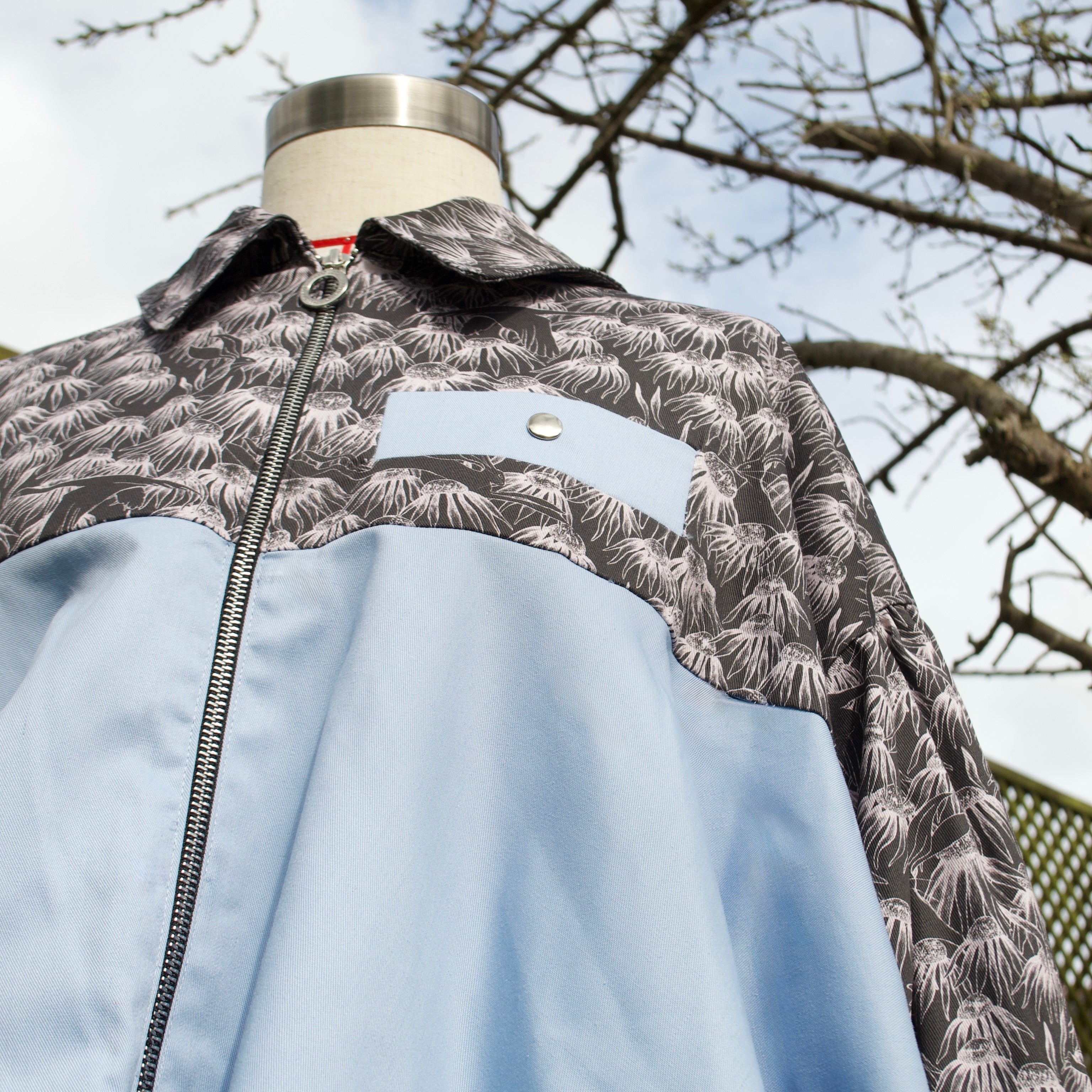 handmade sustainable lightweight jacket for women 100% cotton patterned fabric, black floral print with sky blue contrast bomber jacket with collar and contrast breast pocket, popper fastenings and zip closure 
