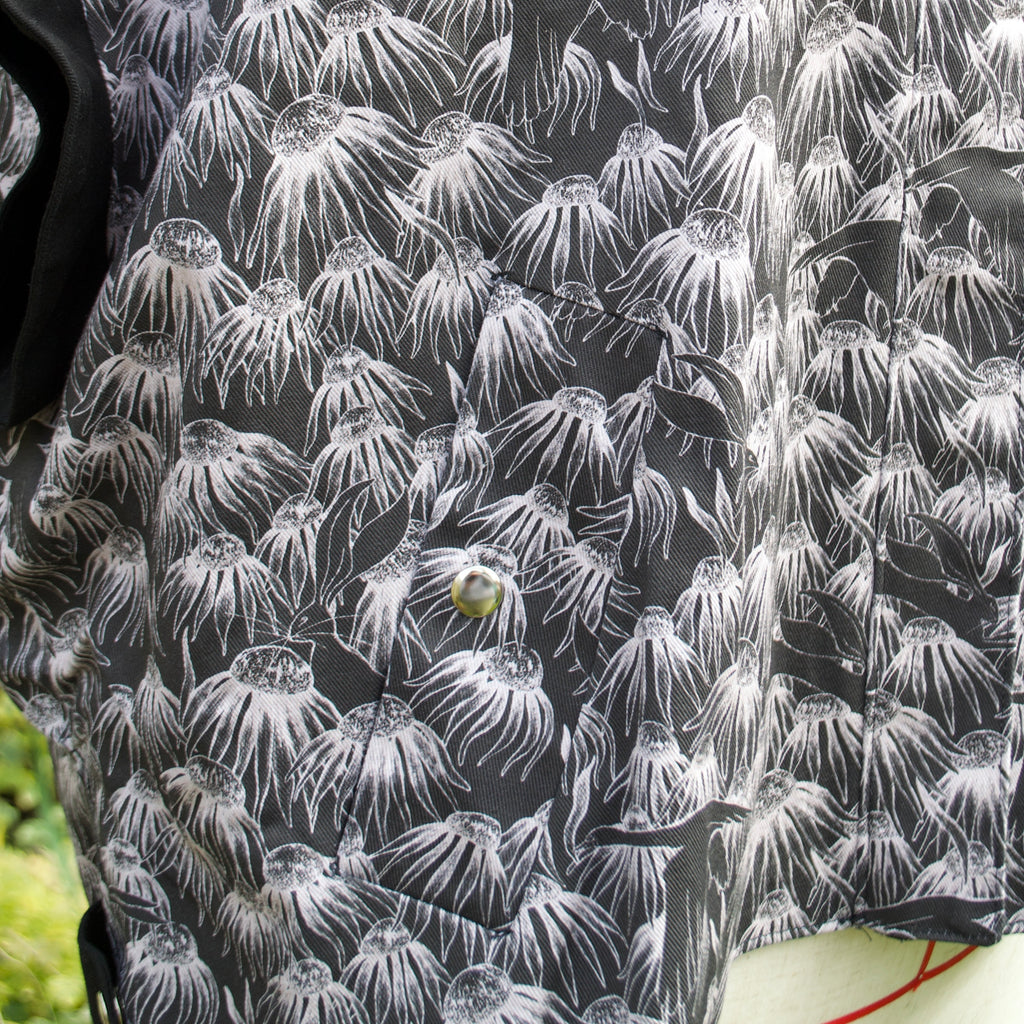 100% cotton lightweight gilet with concealed pockets and side openings for added movement and inclusive sizing. hidden zip closure, whimsical black and white print with flowers, swans and hares perfect for spring summer